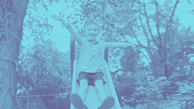 Child sliding down a slide and smiling