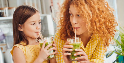 Mother and young daughter drinking healthy juice
